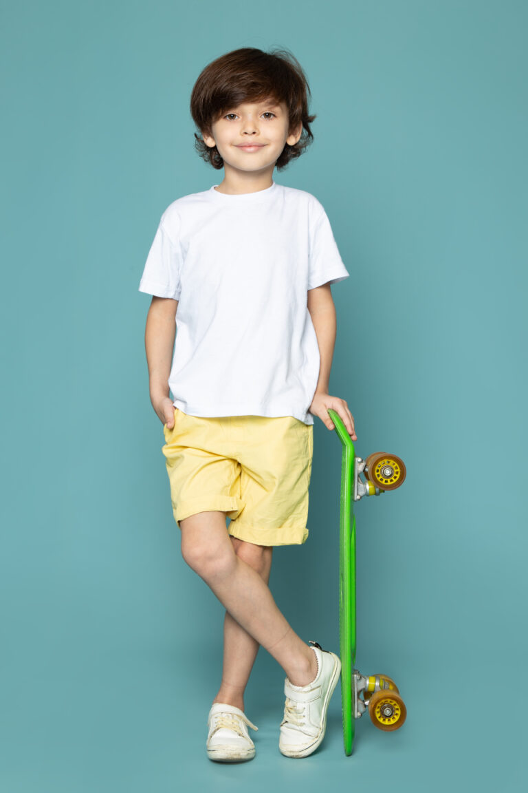 front-view-cute-child-boy-white-t-shirt-yellow-jeans-holding-green-skateboard-blue-floor front-view-cute-child-boy-white-t-shirt-yellow-jeans-holding-green-skateboard-blue-floor